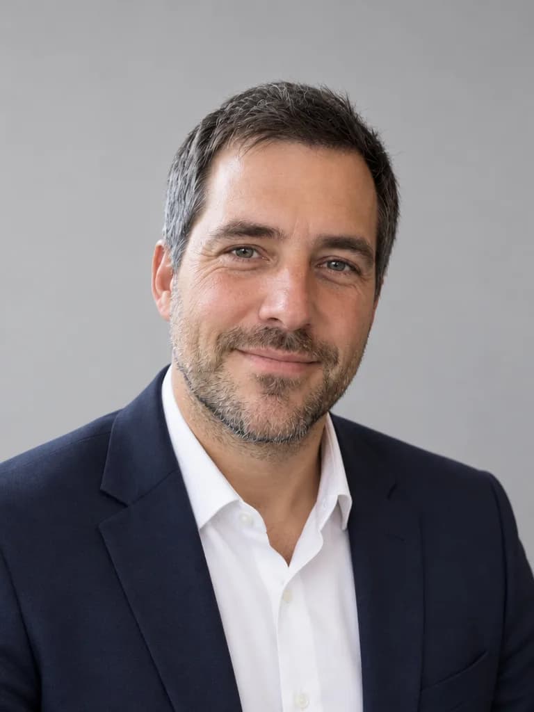 Retrato do homem com blazer azul-marinho e camisa branca diante de um fundo cinza-claro