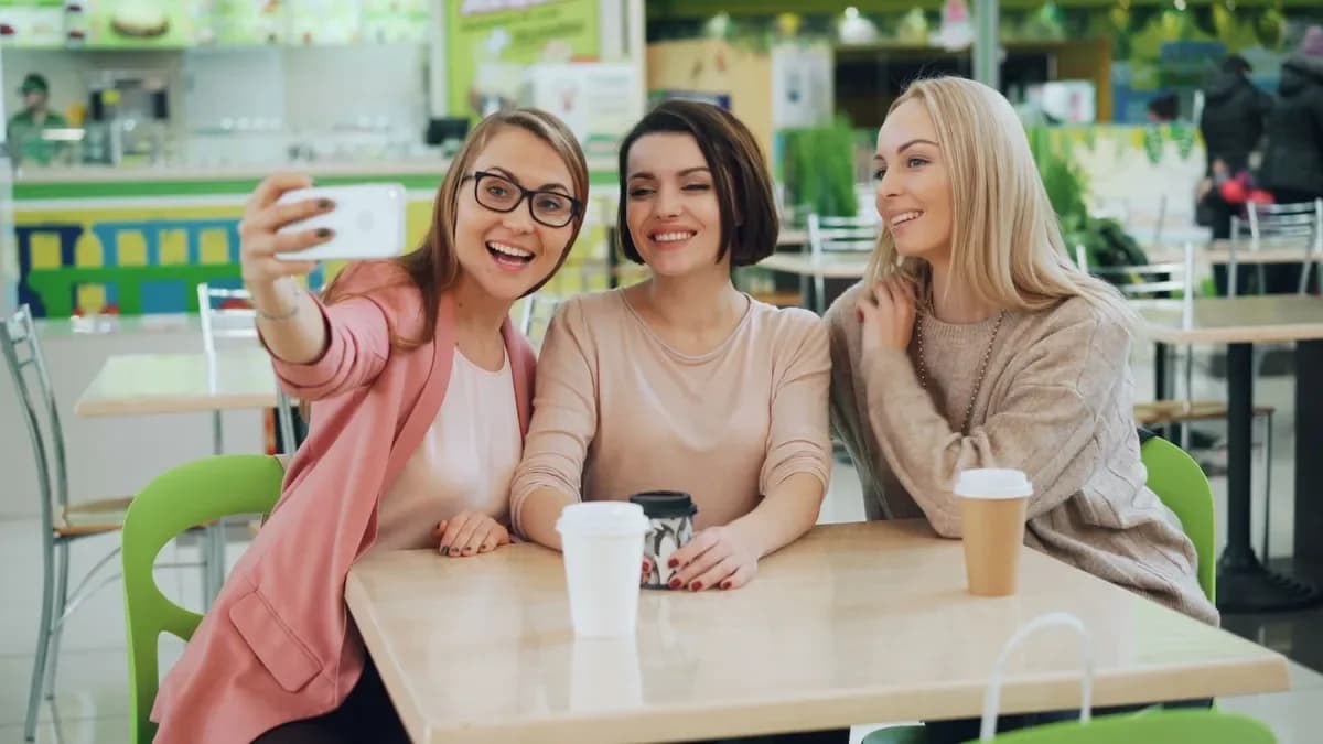 Three women taking a selfie at a café table