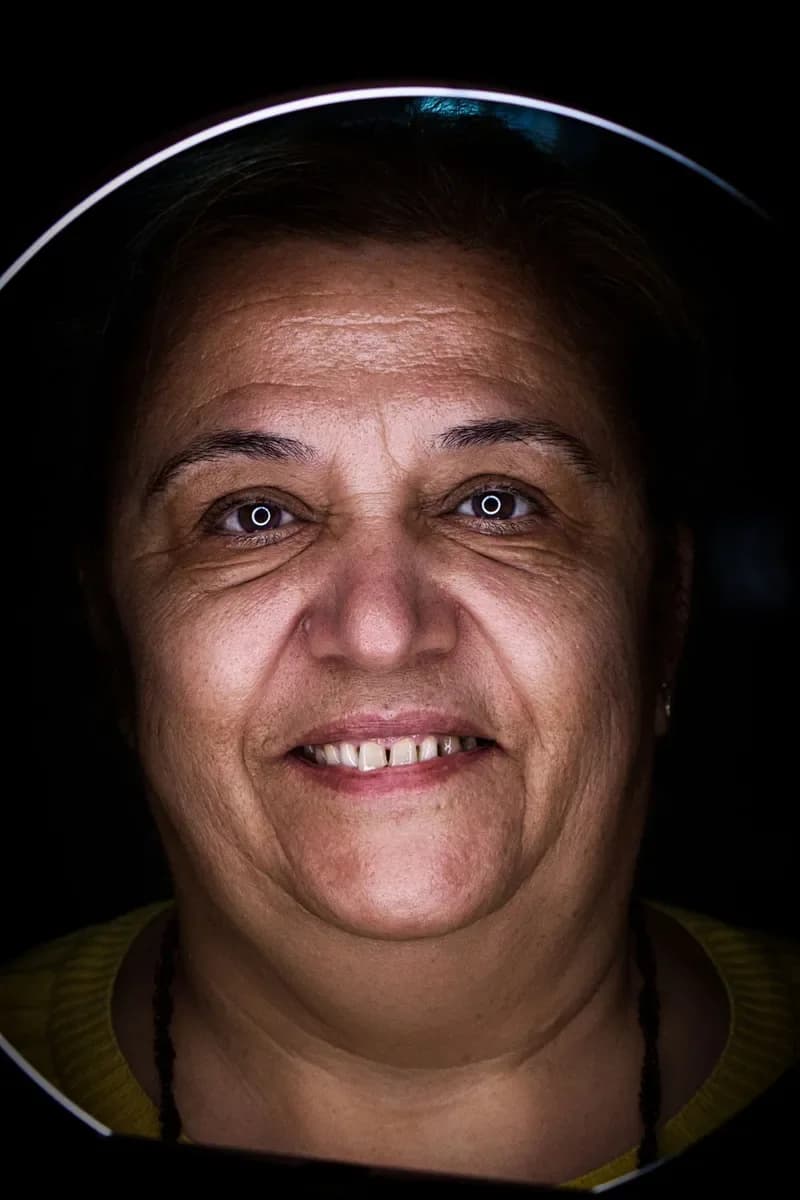 Smiling middle-aged woman on a dark background with lines around her eyes