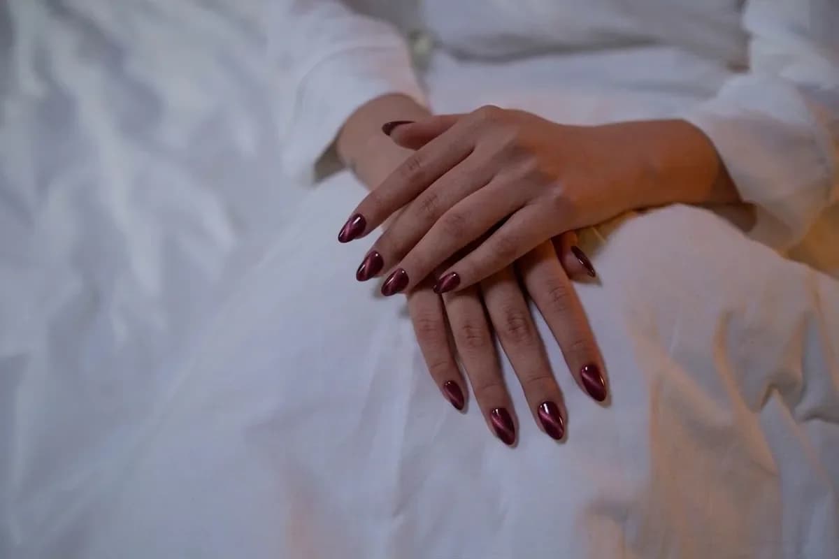 The same hands with burgundy cat-eye nails