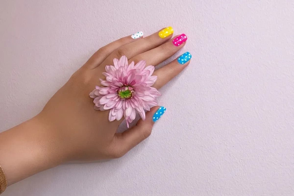 The same hand with multicolor polka-dot nails
