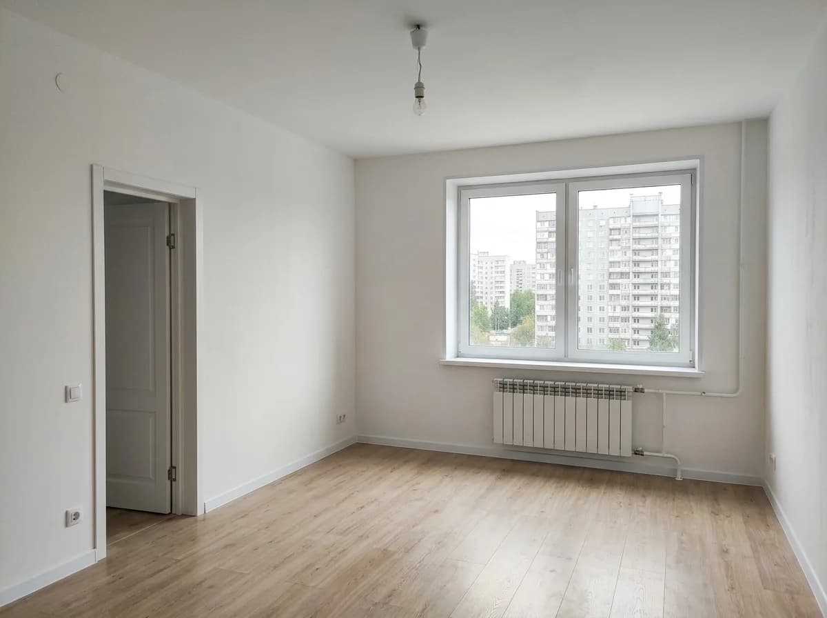 Empty room with a window, a radiator and light laminate flooring