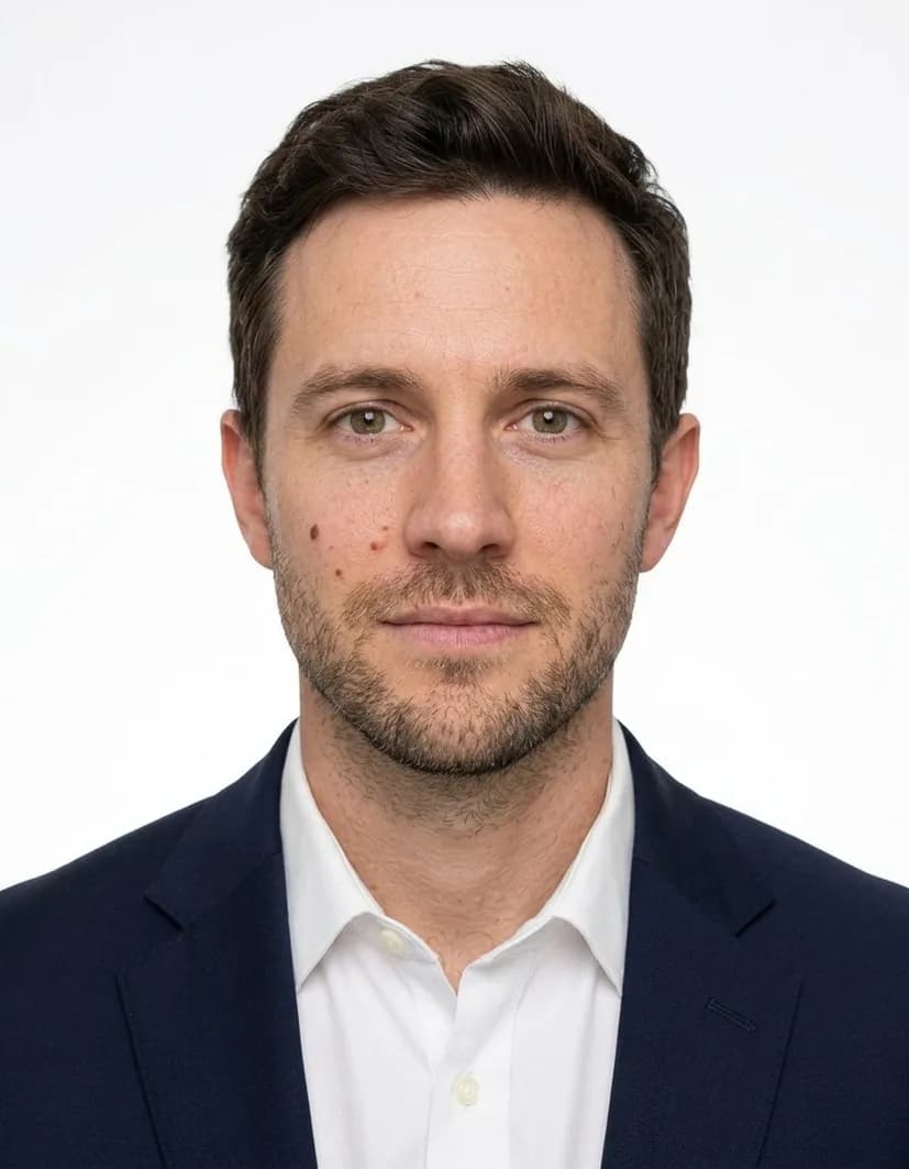 The same man front-facing on a white background in a dark jacket and white shirt